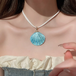 Close-up of blue iridescent shell pendant necklace on white cord with gold accents