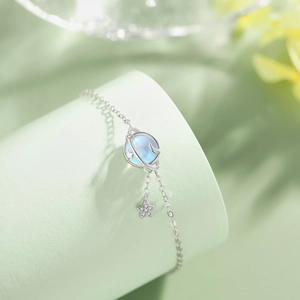 Detail of S925 sterling silver bracelet with light blue planet and sparkling star charms