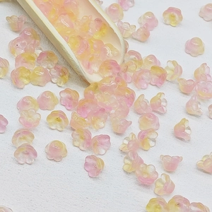 Macro shot of pink and yellow gradient lily of the valley glass beads in a wooden spoon