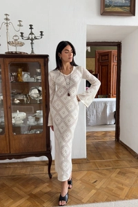 Dettaglio dell'abito lungo in maglia con scollo a V e motivi geometrici a rombi traforati