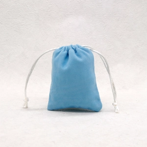 Detailed view of a light blue microfiber drawstring jewelry pouch on a white background