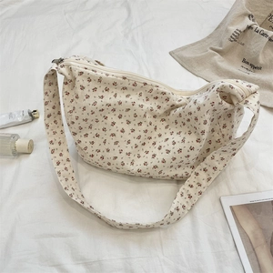 Floral canvas shoulder bag detail on white fabric with casual lifestyle props