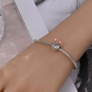 Detailed close-up of a knitting ball charm and pink heart needles on silver bracelet