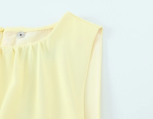 Detail view of bright yellow neckline featuring elegant pleats and a silver metal snap button