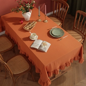 Detailed close-up of orange linen tablecloth with decorative lotus ruffle edges