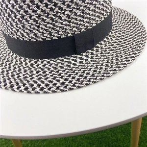 Close-up of houndstooth weave texture and black ribbon detail on a flat-top straw hat