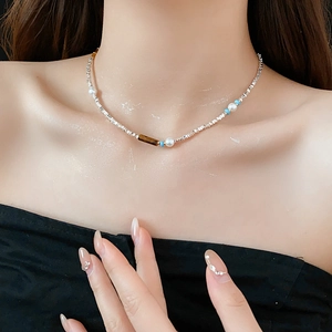 Macro shot of silver beads, pearls, and tiger eye stone on a sparkling model collarbone
