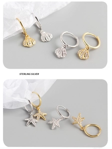 Macro shot of 925 sterling silver starfish and shell charms on gold and silver hoop earrings