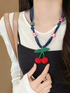Detail of handmade knit cherry pendant with red crochet yarn and green leaf decoration