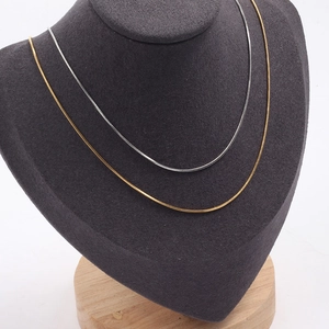 Minimalist gold and silver stainless steel snake chain necklaces on a display bust