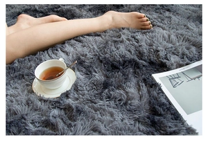 Cozy living room detail of a round dark grey plush rug with book and tea cup
