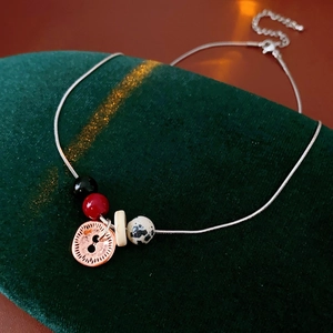 Artistic detail of bohemian necklace with spotted stone pendant on dark green velvet
