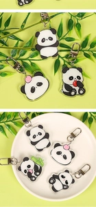 Close-up of cute acrylic panda keychains with bamboo decor and metal clips on a white plate