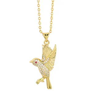 Minimalist gold bird pendant necklace with sparkling white crystals and a tiny red eye stone