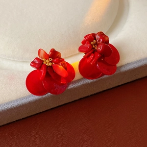 Detail of red flower petal cluster earrings with gold bead centers on velvet