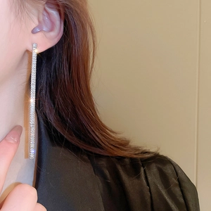 Close-up of long silver tassel earrings with sparkling zircons on a model