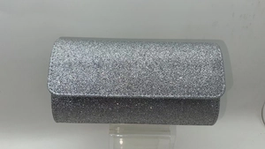Detail of silver sequin evening clutch bag showing textured finish and flap closure