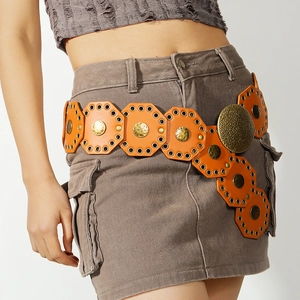Detail view of retro orange octagonal leather belt with brass studs on gray outfit