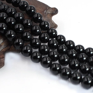 Detailed view of polished black agate round beads for DIY jewelry on a wood stand