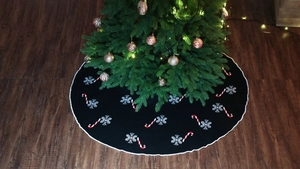 Close-up of black knitted Christmas tree skirt with snowflake and candy cane patterns