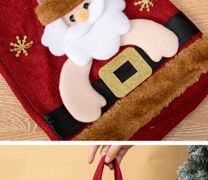 Détail du sac cadeau de Noël en toile de jute rouge avec Père Noël et paillettes brillantes