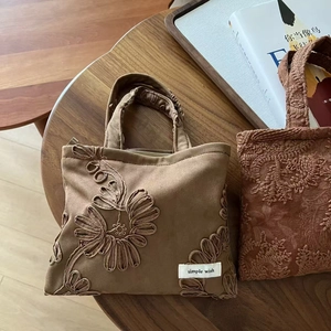 Detail of camel suede tote bags with floral embroidery and simple wish label