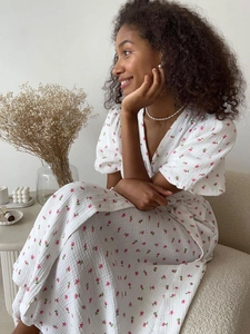 Detail of white cotton floral dress showing puff sleeves, V-neck, and waist tie texture