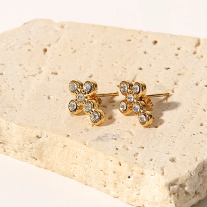 Detail of gold-plated cross earrings with sparkling crystals on a stone display