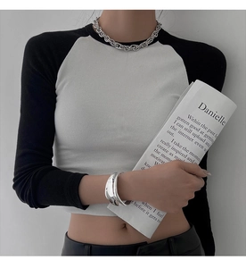Close-up of minimalist irregular wide silver cuff bracelet on model with knit top