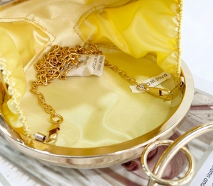 Detail showing the bright yellow satin interior and gold chain of this evening bag