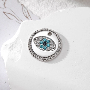 Macro view of silver evil eye pendant with blue crystals on white textured stone