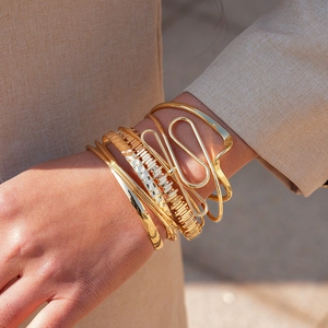 Detail of 6-piece stacked gold geometric metal bracelets on a model's wrist
