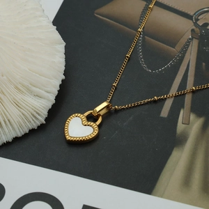Detailed close-up of heart-shaped shell pendant with golden frame and beaded chain