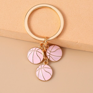 Detail of gold keychain featuring three pink basketball enamel charms with metallic lines