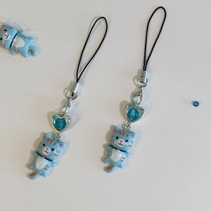 Detail view of two cute Y2K blue cartoon cat charms with blue heart beads and metal clasps