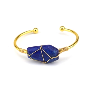 Detailed close-up of wire-wrapped raw blue crystal on a gold-plated open bracelet