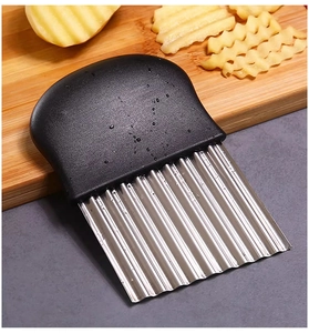 Detail of wavy stainless steel blade slicing potatoes on a wooden board