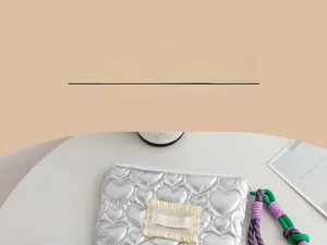 Detail of silver heart-embossed PU leather pouch with colorful braided wristlet strap