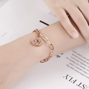 Détail du bracelet en or rose avec fermoir OT et pendentif pièce Elizabeth II au poignet
