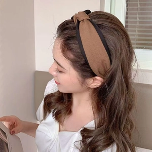 Detail of a brown twisted fabric headband with black trim on a high skull top hairstyle