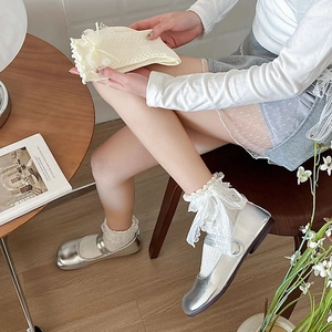 White lace bow socks with silver Mary Jane shoes in a soft indoor aesthetic setting