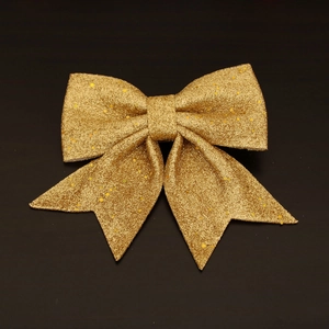 Close-up of a sparkling gold glitter Christmas bow ornament on a black background