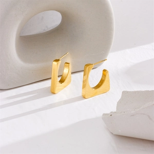 Minimalist gold U-shaped geometric square earrings displayed on a textured stone platform