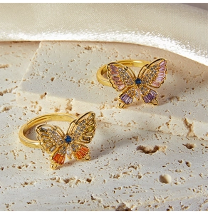 Macro detail of adjustable butterfly rings with colorful cubic zirconia on stone
