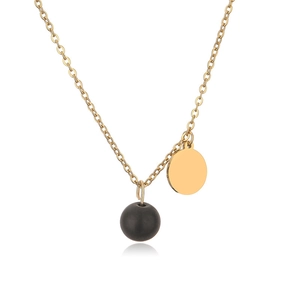 Detail of gold necklace with a matte black bead and flat gold circular pendant