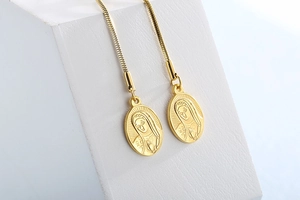Detailed macro view of gold-tone snake chain and oval goddess relief pendant