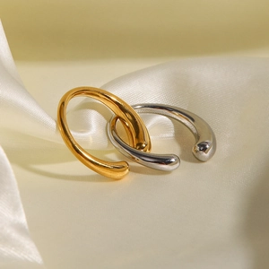 Polished gold and silver titanium steel rings displayed on soft silk fabric
