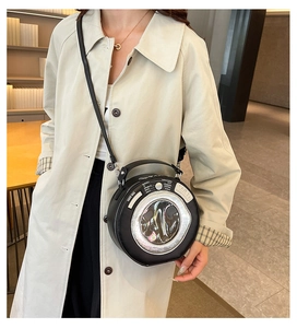 Detail of round black camera-shaped crossbody bag with synthesizer interface design