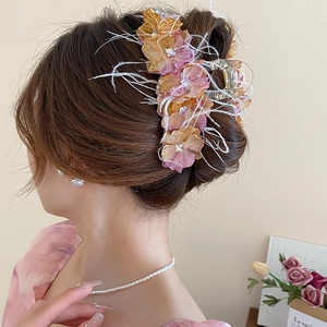 Détail d'une pince à cheveux florale avec fleurs roses, plumes blanches et cristaux