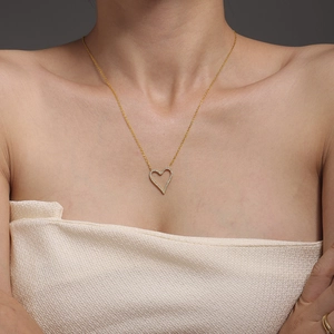 Elegant gold heart necklace with micro-pave crystals worn by a model on grey background